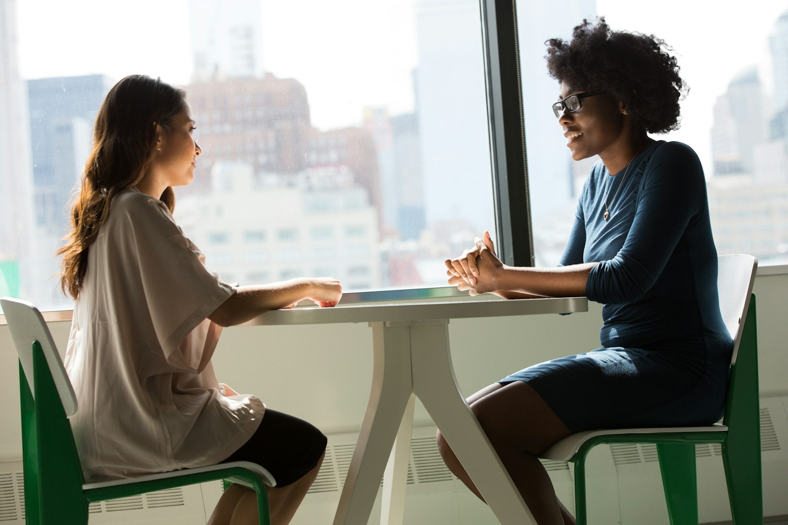 Two women having a face-to-face consultation beside a bright window