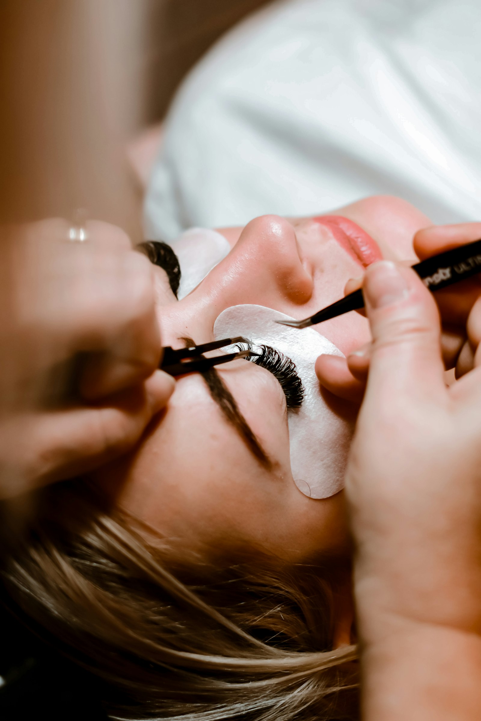A lash professional working carefully on a client's eyelashes