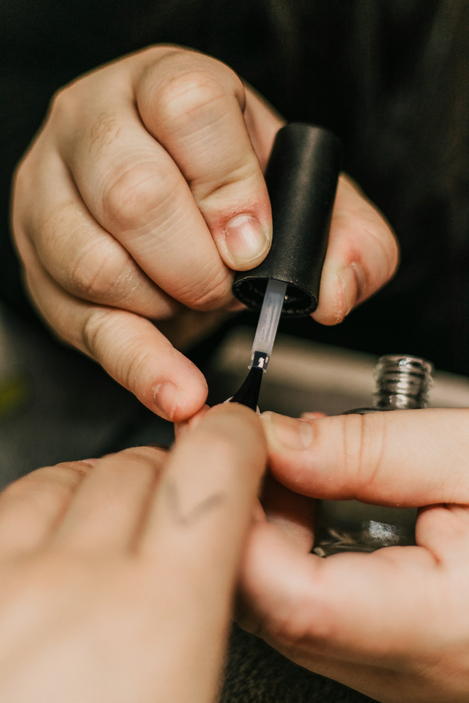A nail professional applying polish during a manicure