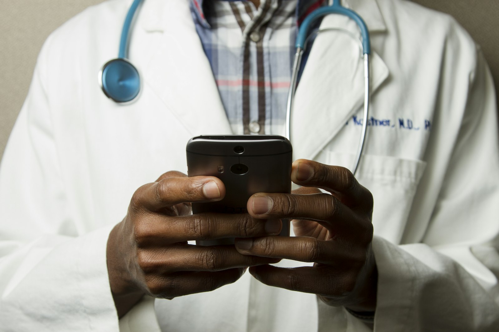 A healthcare provider using a phone with a stethoscope in view
